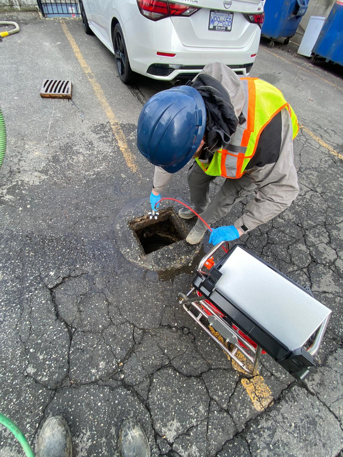Technician preparing line inspection equipment beside a service access point.